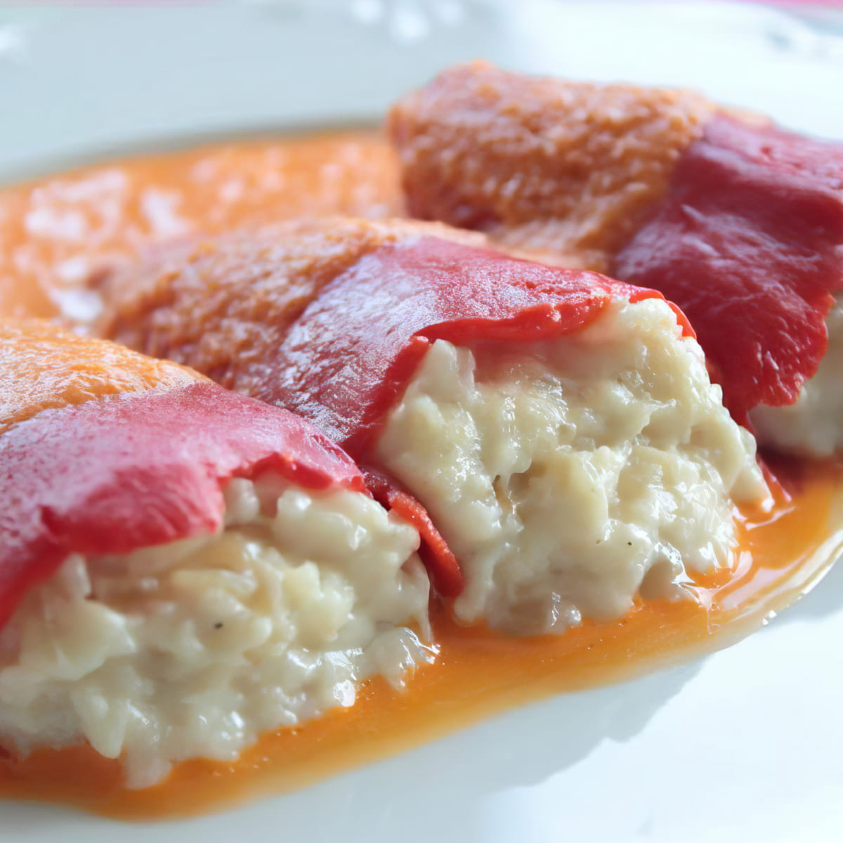 Exquisitos pimientos rellenos de arroz cremoso y queso, servidos con salsa de tomate en Las delicias del monasterio, Madrid.