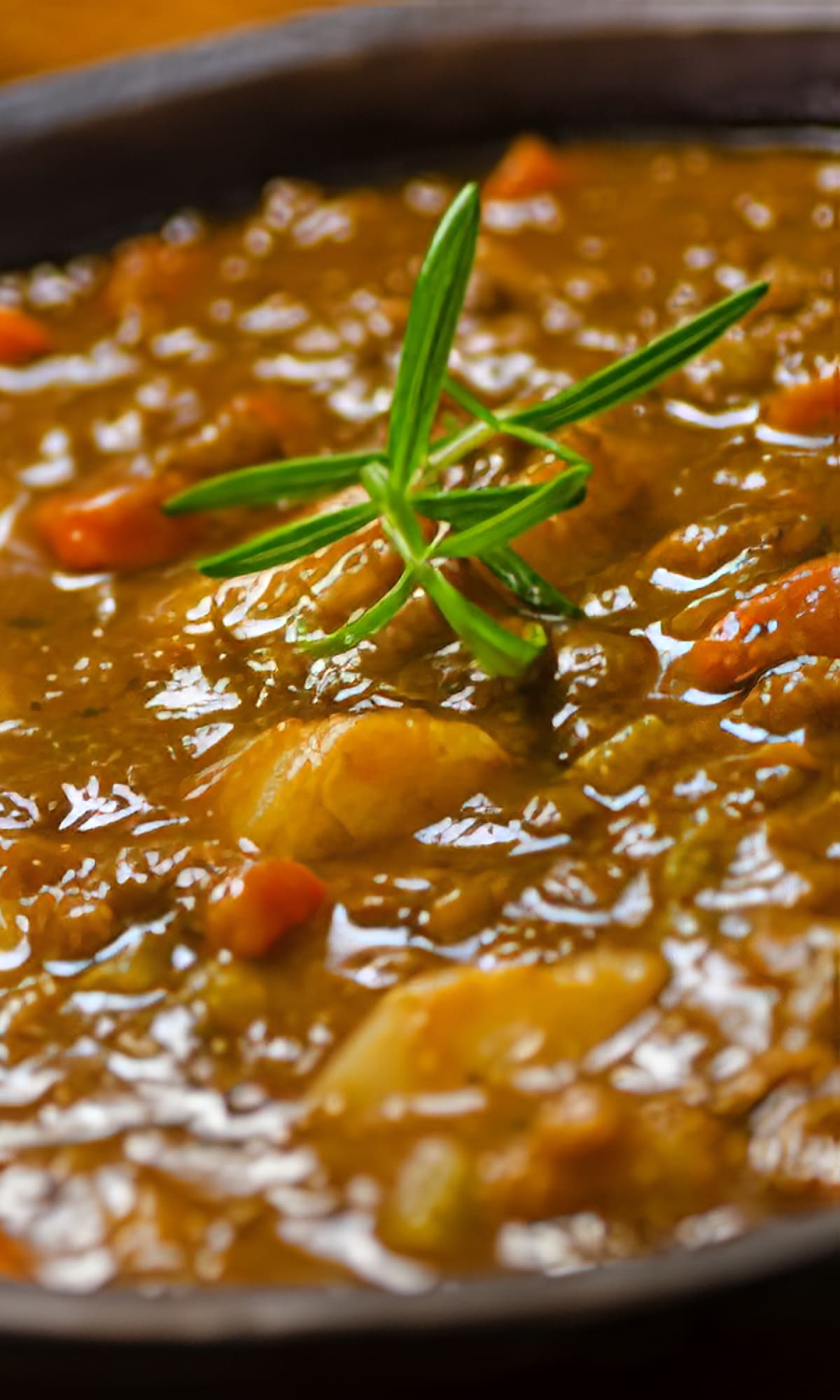 Un cuenco de reconfortante sopa de lentejas casera, adornado con una ramita de romero, de Las delicias del monasterio en Madrid.